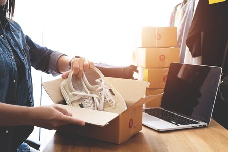 Online selling e-commerce shipping idea concept, Women freelance start up small business owner packing cardboard box at workplaceの写真素材