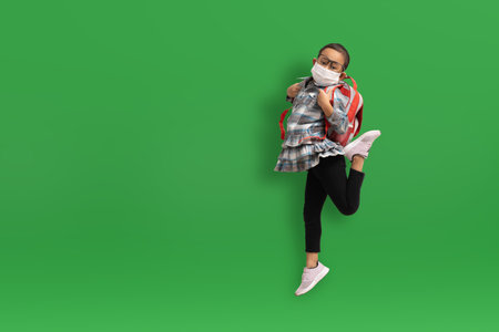 Funny asian child girl wearing medical masks  on green background