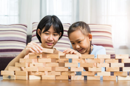 Happy Asian girl with sister play wooden blocks together at home