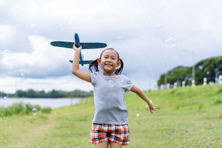 Happy asian little girl runs kite in summer green pasture.の写真素材