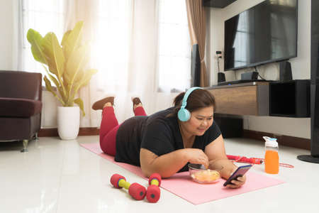 Fat woman asian relaxation vitality using smart phone and junk food at home, Sport and recreation idea concept.の写真素材