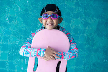 Top view Asian child little girl swims with board in the pool. Swimming lesson idea conceptの写真素材
