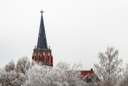 snow powdering their trees visible behind the church towerの写真素材