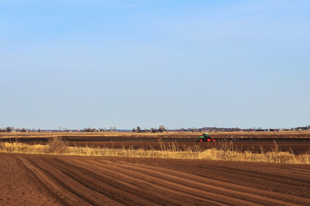 tractor handles Latvia's black land for plantingの写真素材