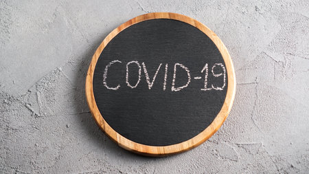 COVID-19 text on black board drawn by chalk.の写真素材