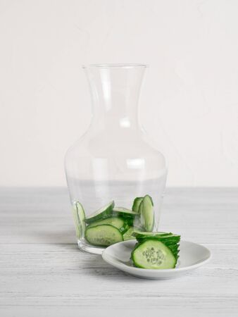 Jar with cucumber slices inside and ingredients on plate for cucumber water recipe.の写真素材