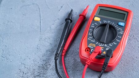 Red multimeter or a multitester, also known as a VOM on gray table. Electronic measuring instrument. Red and black wiresの写真素材