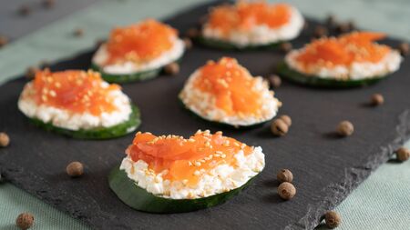 Sandwiches with cucumber at the base, cream cheese and salmon on top on a black tray. Healthy alternativeの写真素材