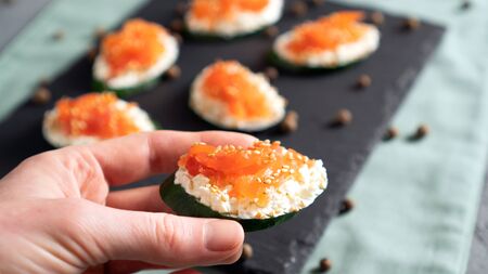 Cucumber with cream cheese and salmon in the hand. Concept of healthy sandwich alternative. Ready to eat.の写真素材