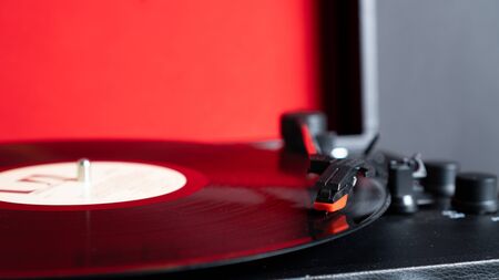 Vinyl needle stylus on rotating black vinyl plate with copy space. Turntable vinyl record player on red backgroundの写真素材