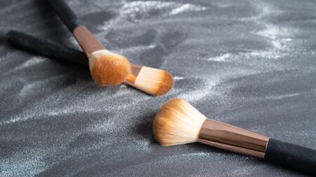 Different size of professional makeup brushes background. White brown bristle, bronze ferrule and black handle brushの写真素材