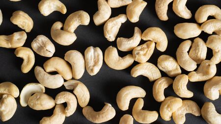 Top view of scattered cashews on a black background. Nuts for heart health, eyes and good for skin. Healthy nuts.の写真素材