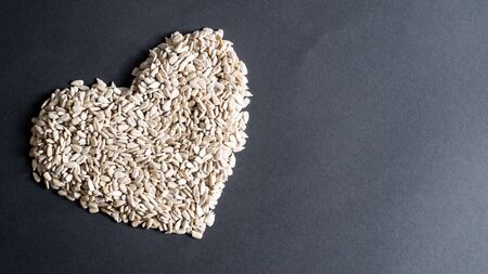 Heart shape of sunflower seeds on black background with copy space. Heap of sunflower seeds in the shape of a heartの写真素材
