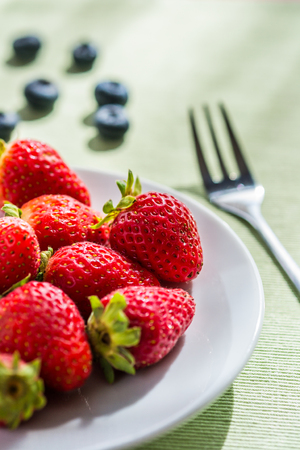 Red strawberries on a white plate.の写真素材