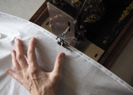 Sewing process. Foot of old vintage sewing machine and hand. Selective focus