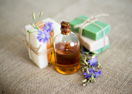 Natural soap and a bottle of aroma oil on jute background. Set of organic cosmetic products,...