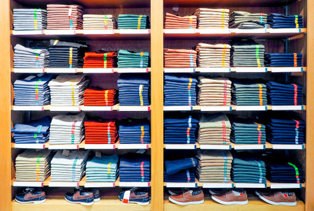 Neat stacks of T-shirts and casual sneakers on the racks in department store. Shopping,...
