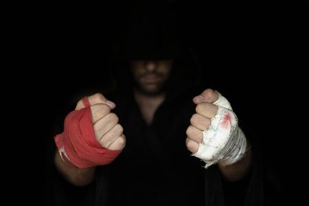 Different kinds of hands taping before rumble. Fists of pro boxer in hoodie, close up, low key, selected focus. Sport, boxing, single combat, training, power, punch, battle and preparation conceptの写真素材