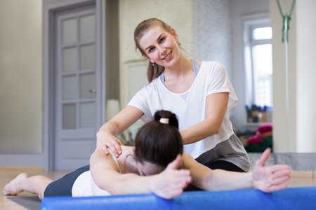 Pilates class in fitness studio indoors. Trainer control a technique of the exercise of a client....