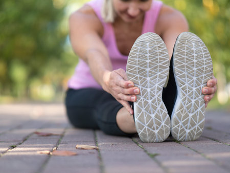 Urban fitness outdoor, selective focus. Feet in sports shoes and hands of woman who doing sitting...