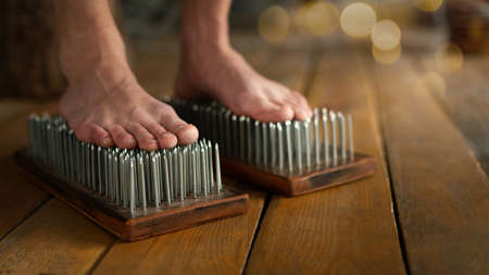 Male bare feet stand on a Sadhu boards with sharp nails on wooden floor indoor, close up, selected focus.の写真素材