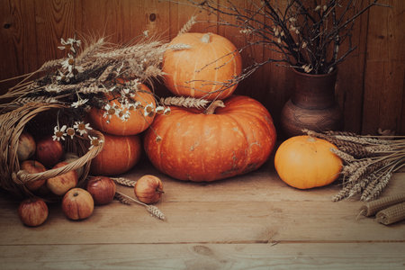 Holiday thanksgiving altar with pumpkins, wax candles, wheat spikelets, daisies, apples and pottery on wooden surface, selective focus.の写真素材