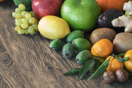 Set of fresh fruits and nuts on wooden table, close-up. Tangerine, kiwi, grape, apple, sweetie, lemon, feijoa, selective focus.の写真素材