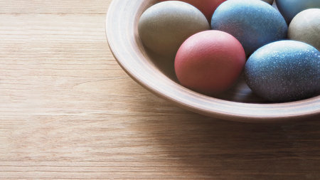 Clay plate with colored eggs for Easter on wooden surface, close-up, copy space. Ostara, spring, symbol, tradition, detail, religion, March concept.の写真素材
