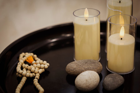Atmospheric set of accessories in spa salon. Candles, stones and rosary, copy space, selective focus. Massage salon, aromatherapy, treatment, relax, services concept.の写真素材