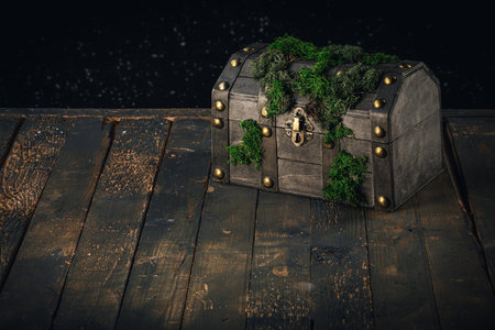 Decorative atmospheric pirate treasure chest covered with moss on an old wooden background, copy...