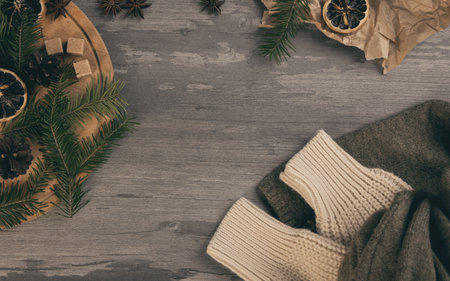Atmospheric Christmas set. Spruce twigs, star anise, dried orange slices, brown sugar, baking paper and knitted sweater sleeves on a wooden background, copy space.の写真素材