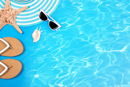 Beach holidays set. Striped summer sunhat, female sandals, seashell, sunglasses and starfish on blue background with the texture of sea waves, flat lay.の写真素材