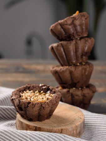 Brown muffin on wooden stand on striped fabric, pyramid of cupcakes on background, copy space, vertical image. Cooking, baking, homemade food, pastry, kitchen, cupcake concept.の写真素材