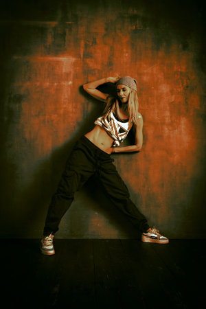 Stylish Caucasian young woman dance hip hop, movement. Art processing in green and orange tones.の写真素材