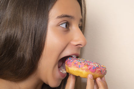 Portrait of a pleased pretty,cute baby girl eating sweet donuts .の写真素材
