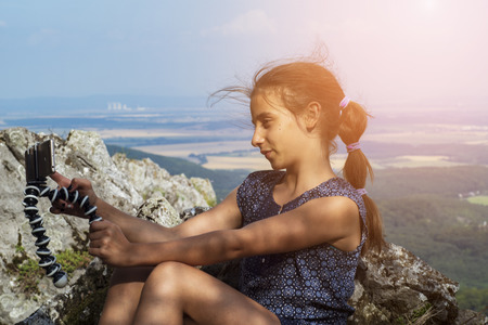 The girl sits on the mountain and looks into the distance.の写真素材