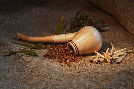Smoking pipe with tobacco leaves on wooden background,Smoking pipe, Pipe for tobacco. Dry tobacco for smoking.の写真素材