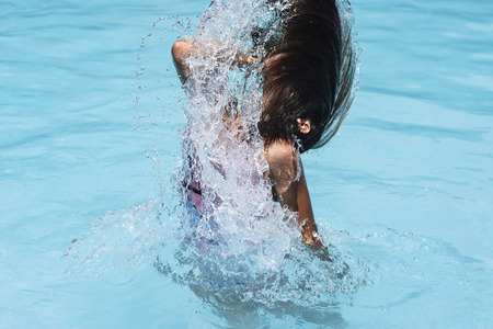 Motion freeze on a girl splashing the sea water with her hairの写真素材