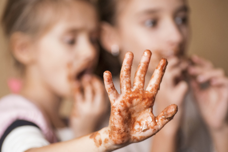 Girls, children eat chocolate, a mouth and hands of girls are smeared with chocolate.Girls, children eat chocolate.の写真素材
