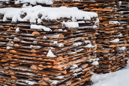 Woodpile stacked of firewood under the snow. Stack of cut wood under the snow.
