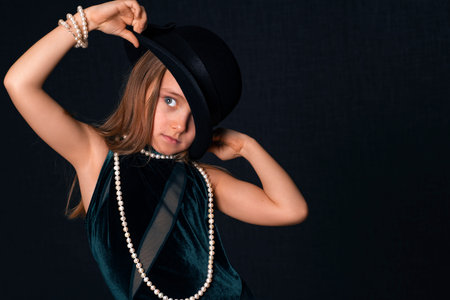 Little girl in a black hat and white beads.Portrait of a beautiful little girl in retro style in an...
