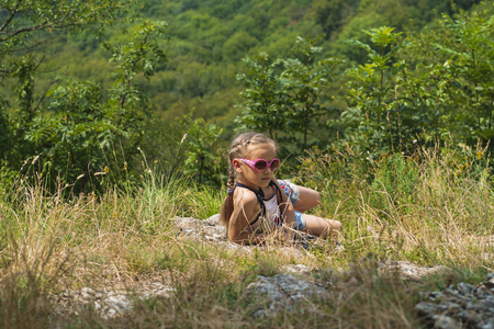 The girl sits on the mountain and looks into the distance.Summer sunny day. Time to rest.の写真素材