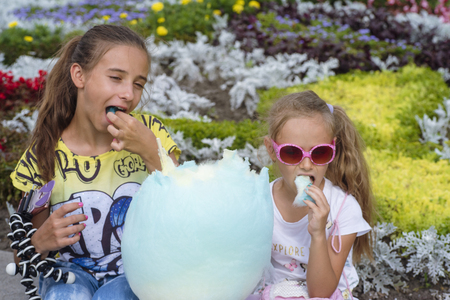 A to little charming girl eating huge cotton candy .Summer sunny day. Time to rest.Sweet cotton candy.の写真素材
