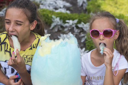 A to little charming girl eating huge cotton candy .Summer sunny day. Time to rest.Sweet cotton candy.の写真素材