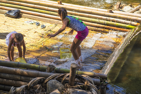 On the banks of the river girl holding fish caught in the river.Girls on a summer day catch fish on the river.の写真素材