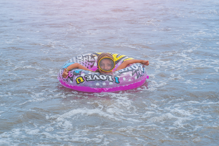 On the face is a water mask. Happy Smiling girl enjoys floating on inflatable donut in sea. vacation time.の写真素材