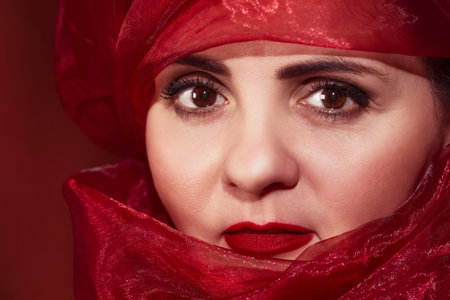 Beautiful arab woman in a red headdress. Portrait of an Arab woman. Portrait close-up.Young woman in...