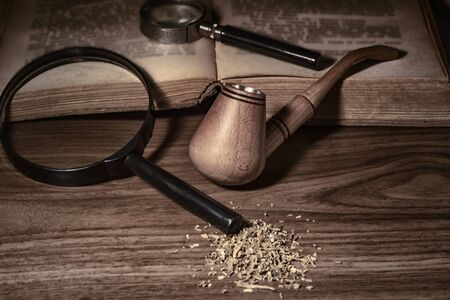 Smoking pipe with tobacco leaves on wooden background.wooden background.Wooden pipe with smoke on heap of chopped dried tobacco leaves against black background.の写真素材