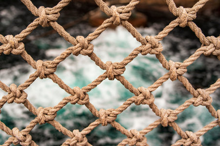 Background from a strong rope on a background of blue water.Close-up of an old frayed boat rope as a...