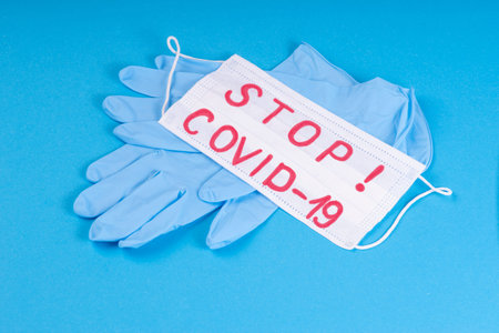 Blue medical gloves on a blue background with a white medical mask with a respirator.